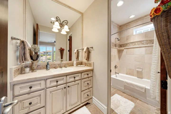 Bathroom featuring a distressed wood-finish vanity with an integrated sink, framed mirror, and decorative light fixture