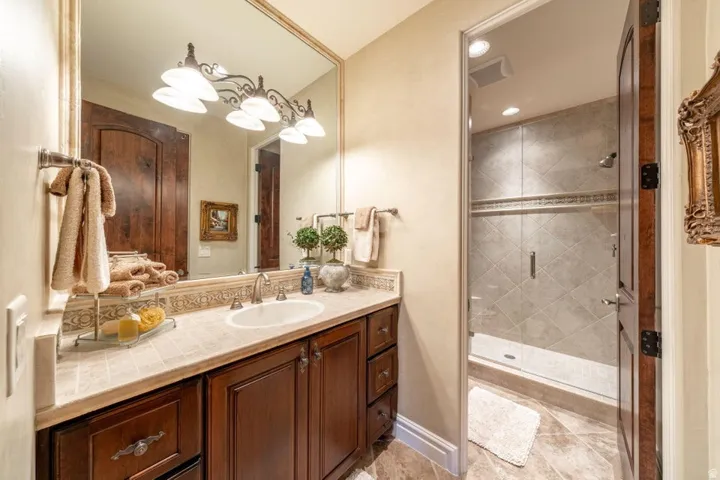 Wood-finish vanity with an integrated sink, stone countertop, and custom tile backsplash