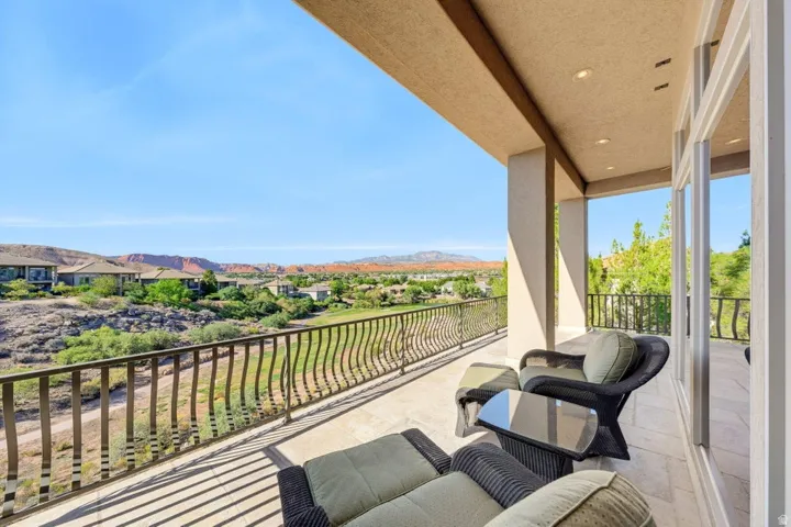 Expansive covered balcony featuring tile flooring and decorative metal railings