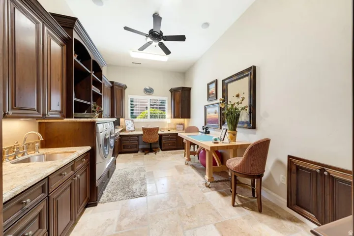 Built-in cabinetry, under-cabinet lighting, a utility sink, and stone-finish countertops