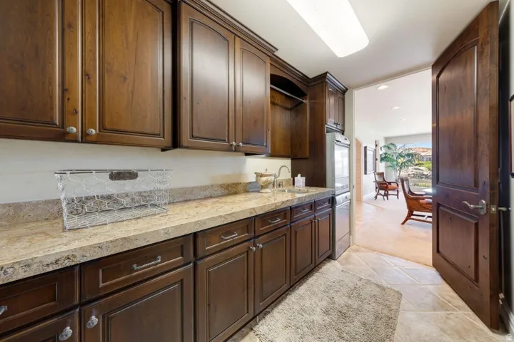 Spacious utility area featuring extensive wood-finish cabinetry, a built-in sink, and light-toned countertop