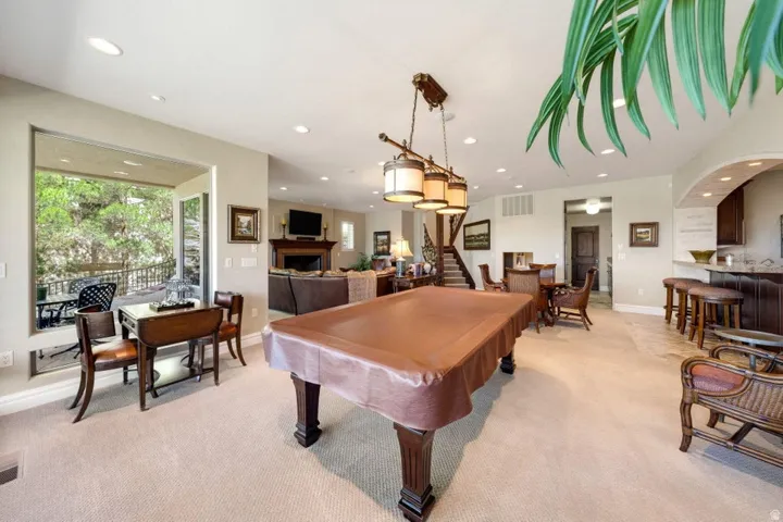 Recessed lighting, wood-finish wet bar with arched entry, and a built-in staircase