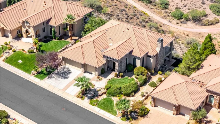 Terracotta tile roofing, stone-clad exterior, multi-car garage, mature landscaping, and an upper-level balcony