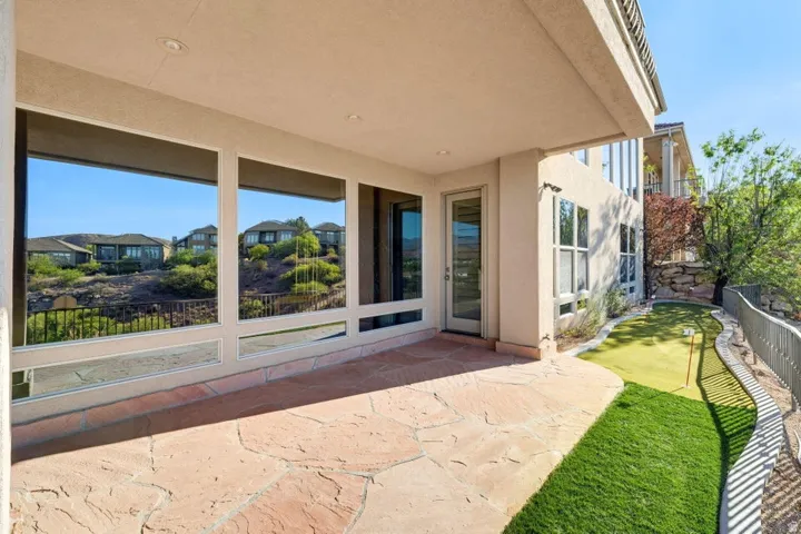 Covered patio with flagstone flooring, large windows, an exterior door, and a putting green