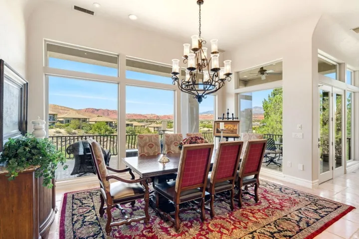 Spacious dining area featuring a large window array, glass patio doors, and a multi-tiered chandelier