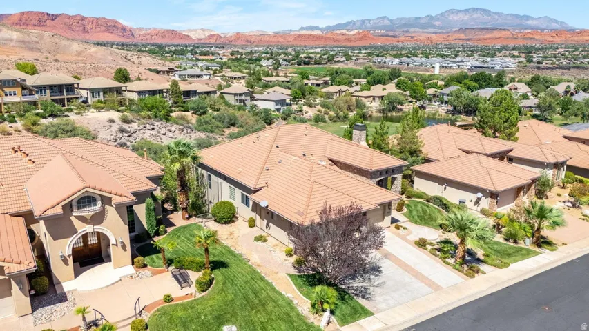 Tile roof with a stucco exterior, featuring a paved driveway and mature landscaping