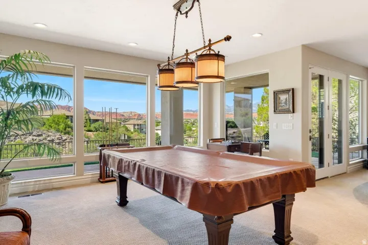 Expansive windows frame distant mountains and lush greenery, complemented by recessed lighting and a multi-light pendant fixture