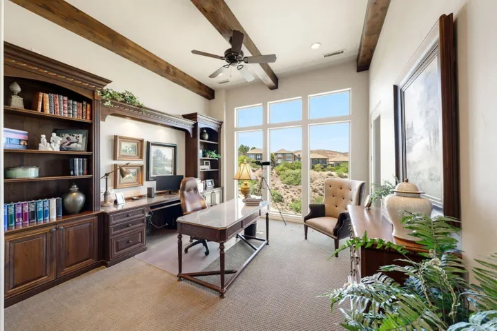 Built-in wood cabinetry with shelving, exposed wood ceiling beams, and expansive windows