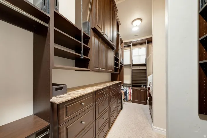 Built-in shelving, extensive cabinetry, light-colored carpeting, recessed lighting, and a marble-finish countertop