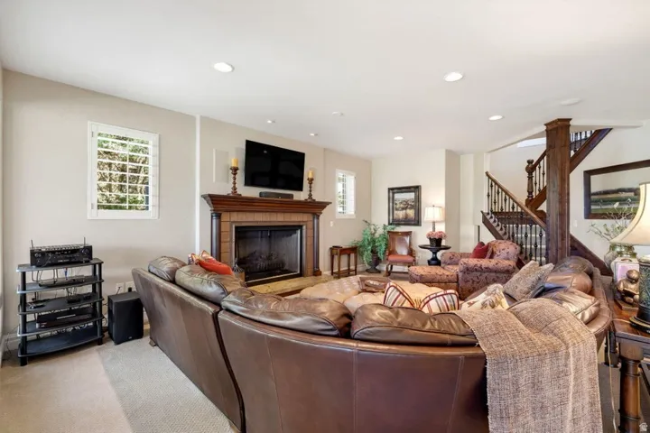 Recessed lighting, fireplace with wood mantel, built-in shelving, wood staircase with dark balusters, and plantation shutters