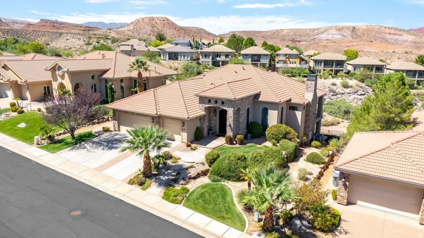 Stucco exterior with stone accents, tile roof, attached two-car garage, and desert landscaping