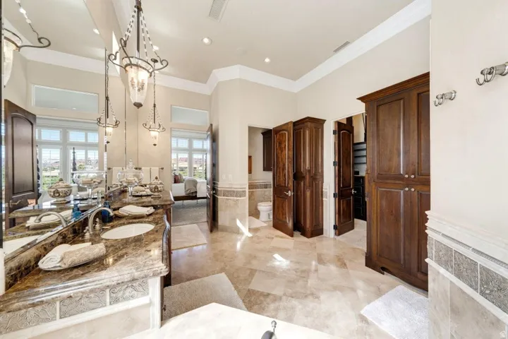Dual undermount sinks set within a stone-finish countertop, flanked by two ornate pendant light fixtures