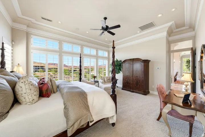 Expansive window wall with plantation shutters, recessed lighting, ceiling fan, crown molding, and plush carpeting