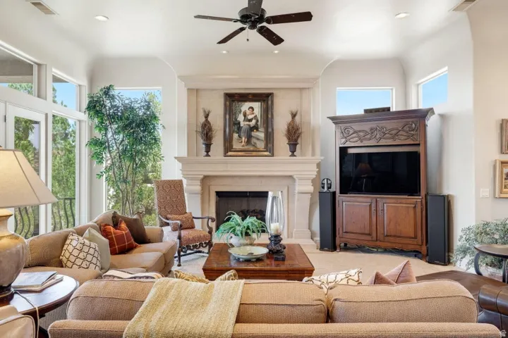 Arched fireplace with mantel, ceiling fan, recessed lighting, and large glass paneled doors
