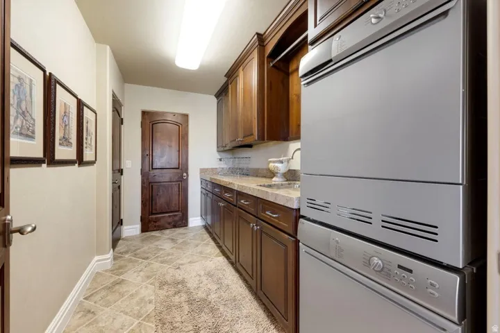 Utility area with wood cabinetry, light-toned countertop, and integrated stainless steel appliances