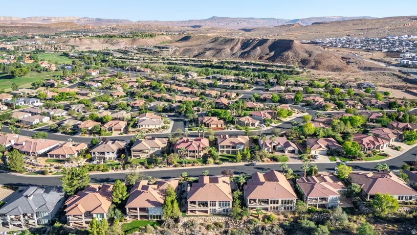 Residential community with varied architectural styles and mature landscaping, surrounded by natural desert terrain and distant mountains