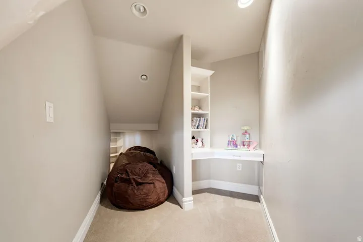 Recessed lighting, built-in shelving, integrated desk, and neutral carpet flooring