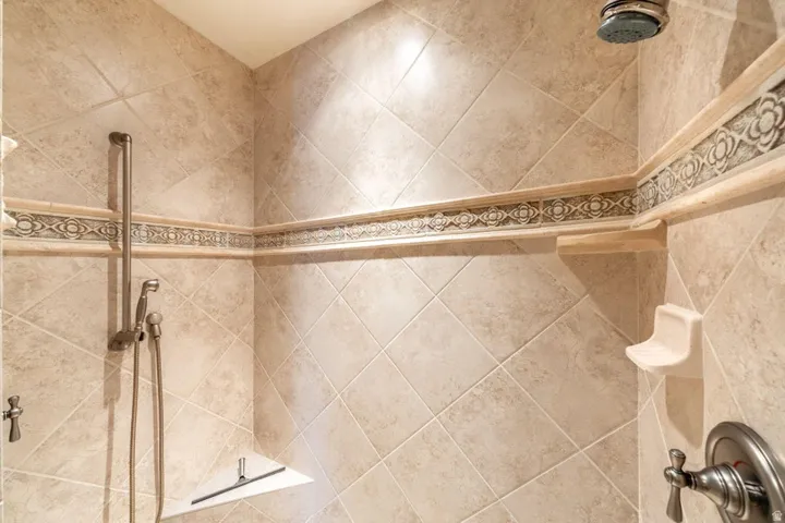 Diagonally laid shower wall tiling with decorative accent trim