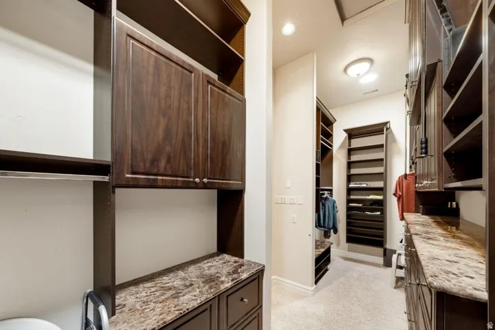 Custom dark wood-finish cabinetry, integrated shelving units, granite-style countertops, and recessed lighting