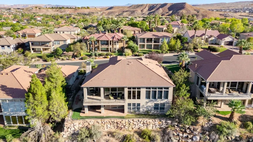 Terracotta roof tile, multi-story structure, covered balcony, extensive window placement, and mature landscaping