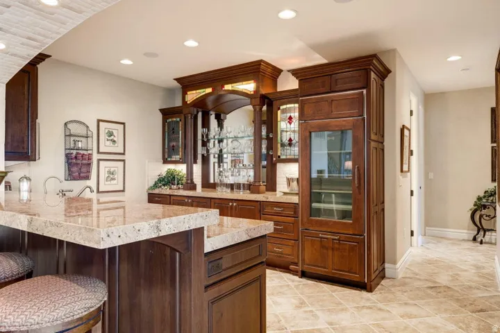 Built-in bar featuring wood cabinetry, recessed lighting, stone countertops, and a beverage refrigerator
