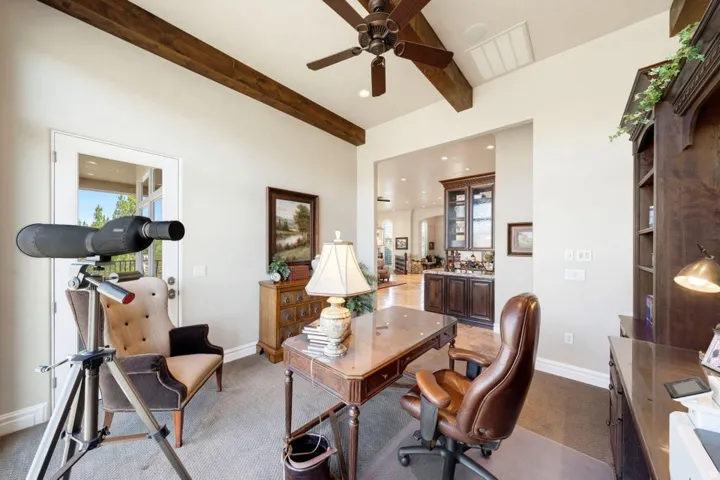 Room featuring exposed ceiling beams, a ceiling fan, and a built-in dark wood bookcase