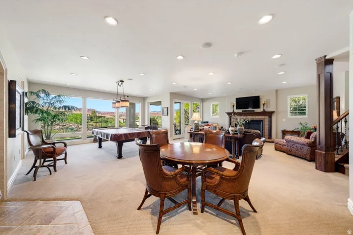 Recessed lighting illuminates the carpeted living area with a brick fireplace, wood mantel, and built-in media console