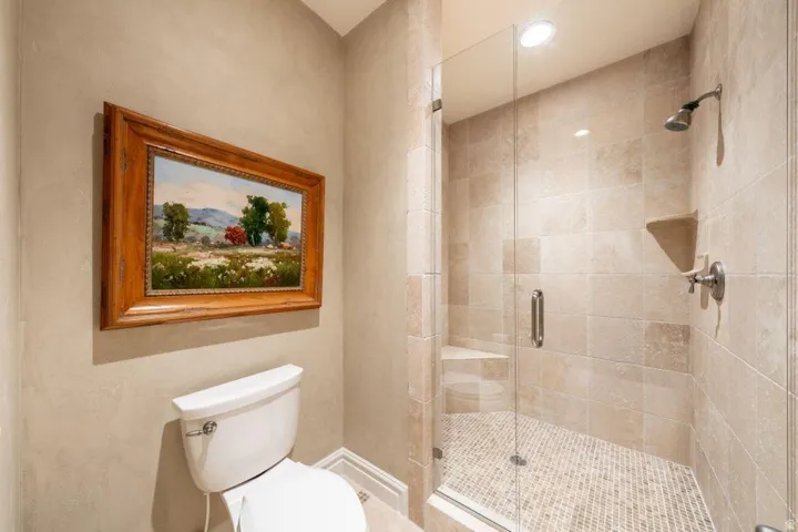 Glass-enclosed shower with tile surround, mosaic tile flooring, and integrated corner bench