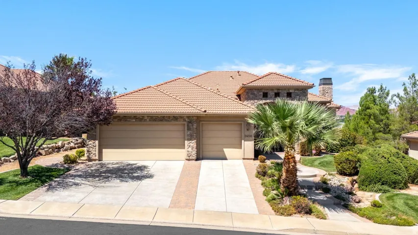 Exterior featuring a tile roof, stone accents, and a two-car garage