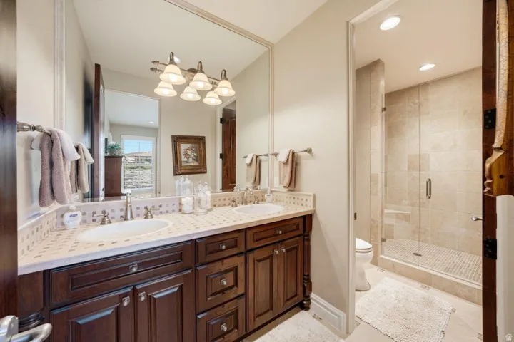 Dual vanity with dark wood-finish cabinetry, integrated sinks, and tiled countertop