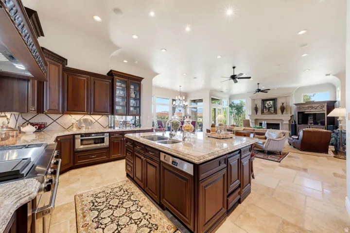 Open-concept kitchen and living area featuring wood-finish cabinetry, stone flooring, and recessed lighting