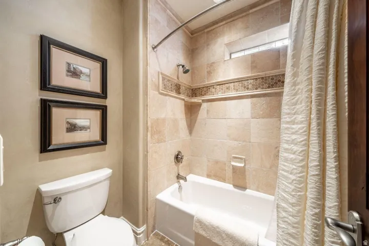 Tile-surrounded bathtub with an integrated shower head and a decorative mosaic accent band