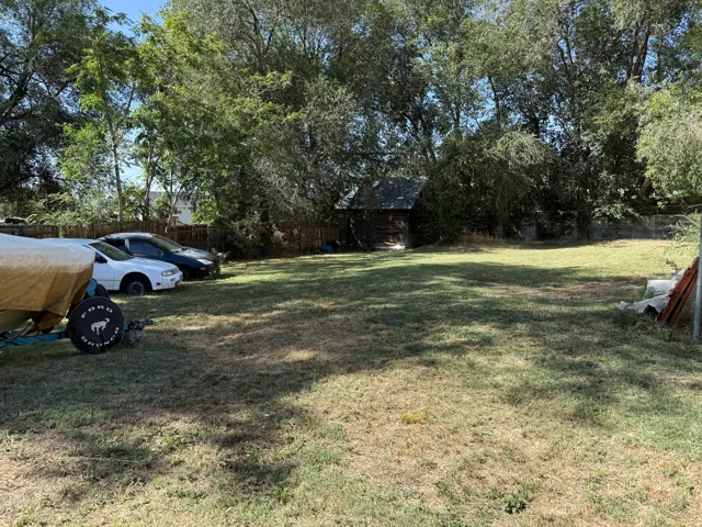 Expansive grassy area with mature perimeter trees and a rustic shed structure
