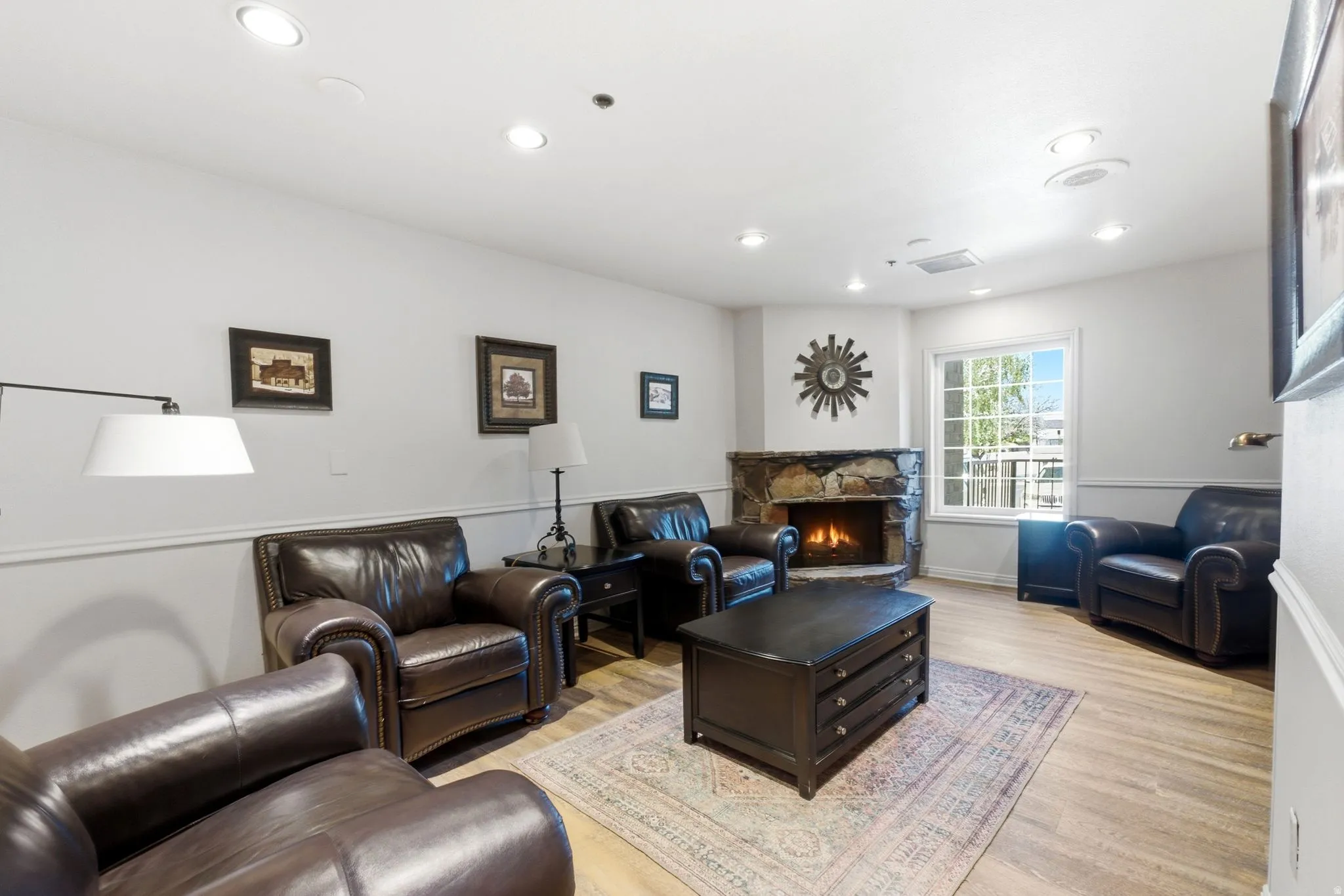 Corner stone fireplace with a built-in mantel, recessed lighting, wood-finish flooring, and crown molding