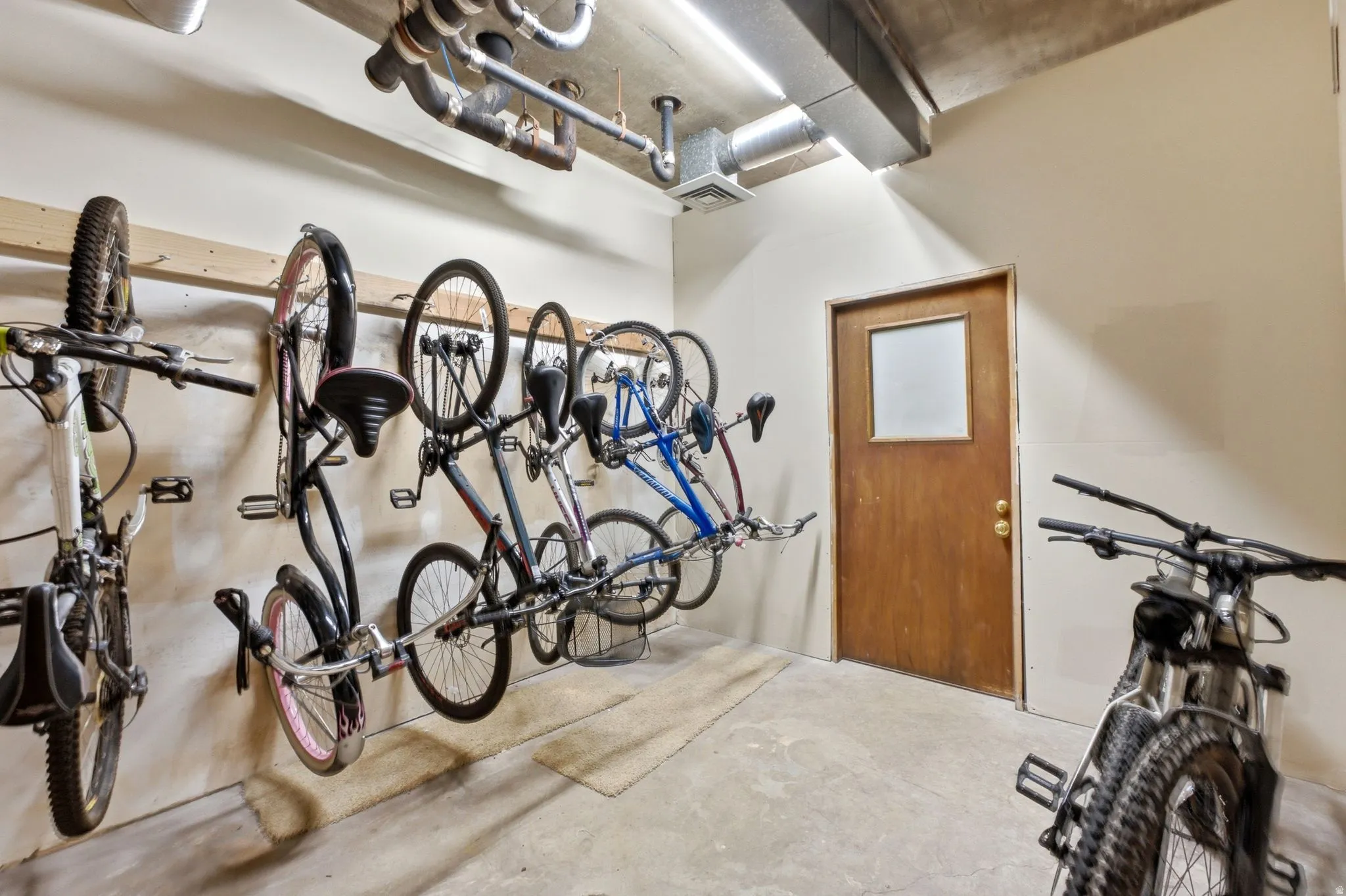 Dedicated storage area featuring concrete flooring, track lighting, and exposed ceiling utilities