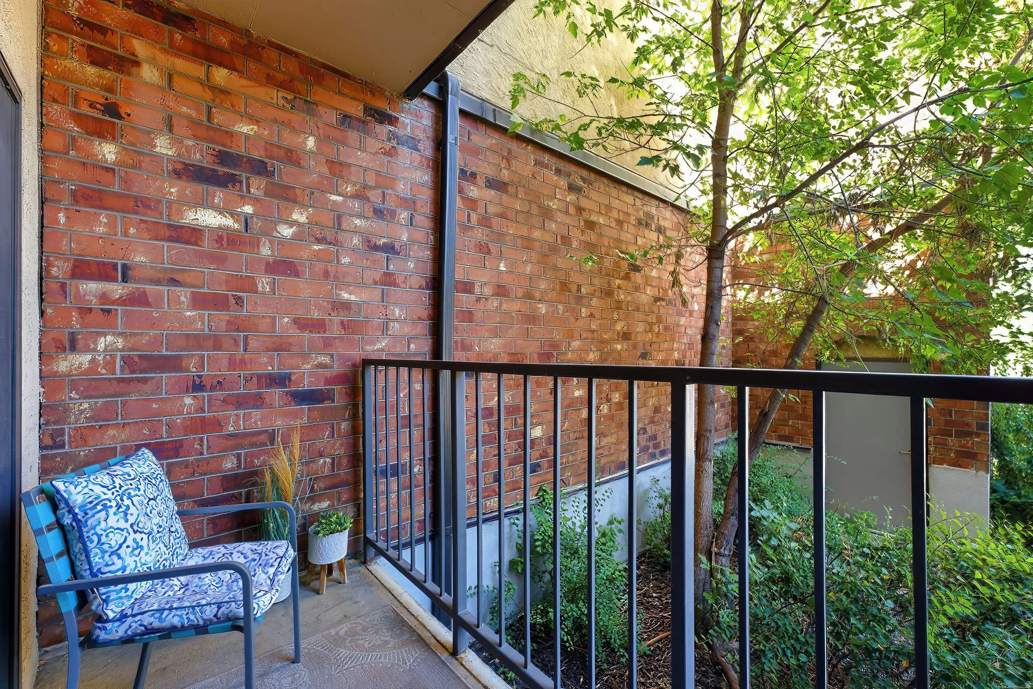 Balcony with a red brick wall, black metal railing, and a concrete floor