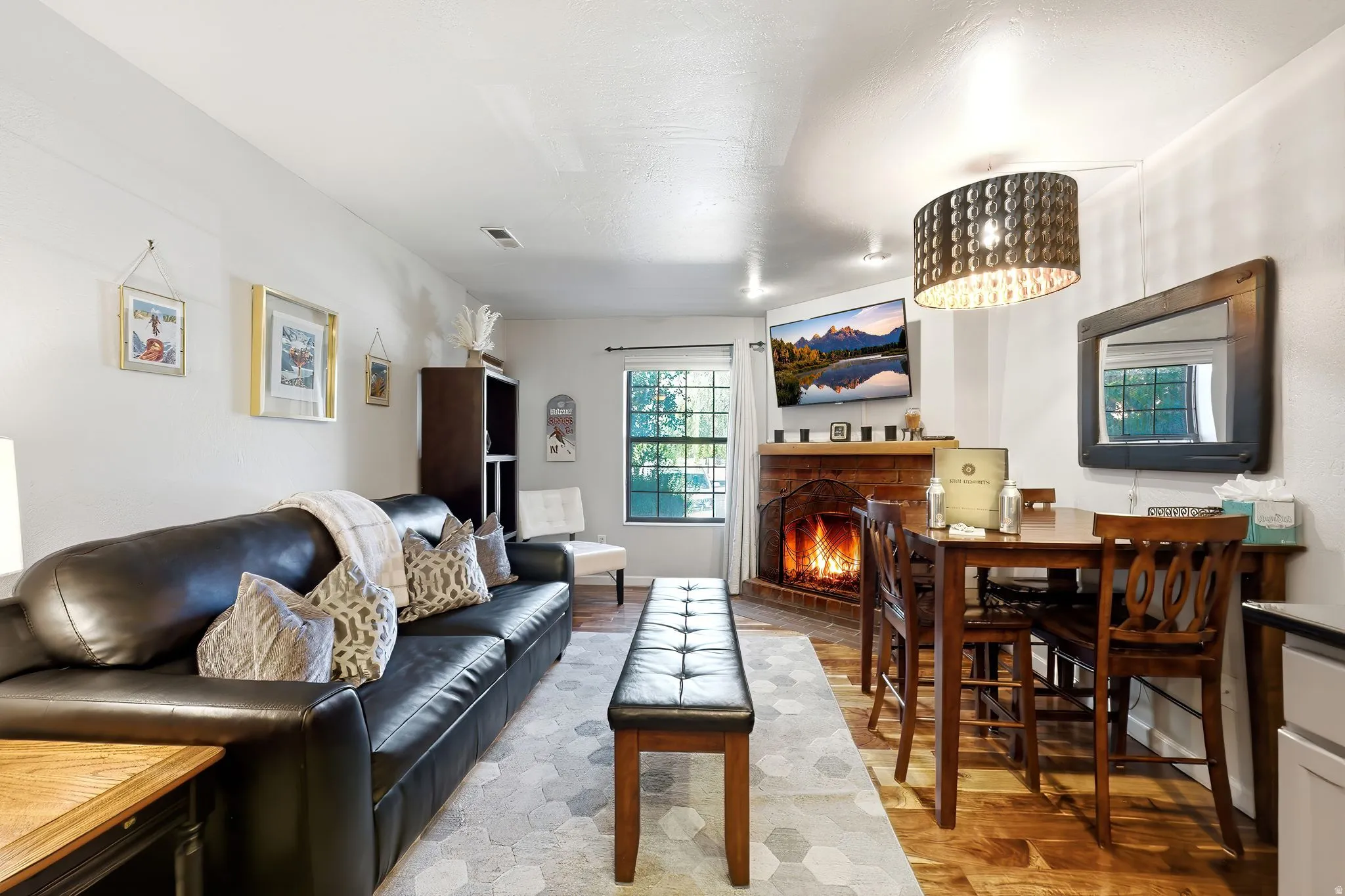 Corner fireplace with brick surround, wood-finish flooring, and recessed lighting