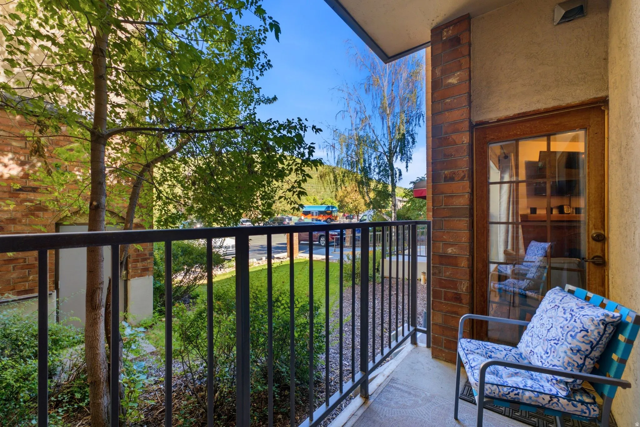 Private balcony with a brick-clad wall, wood-paneled door with glass inserts, and black metal railing