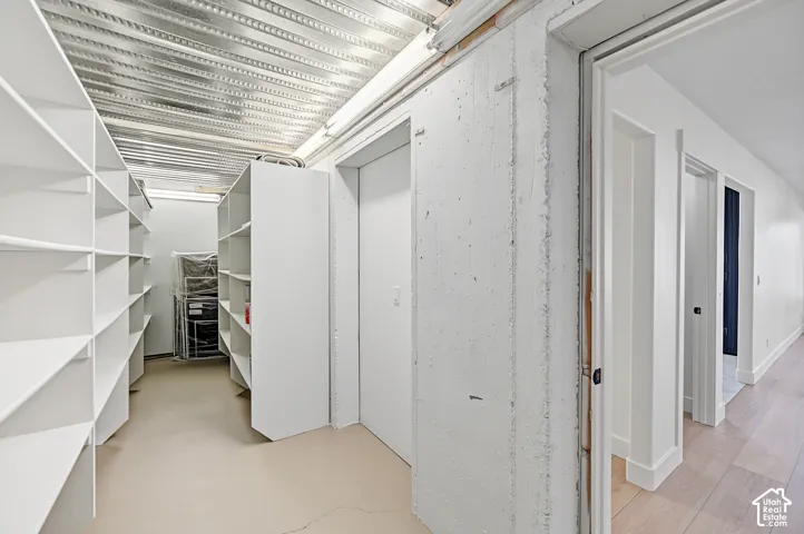 Storage area with extensive white shelving, concrete walls, and metal ceiling