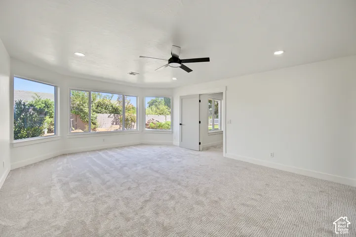 Spacious room featuring multiple windows, recessed lighting, a ceiling fan, and carpet flooring