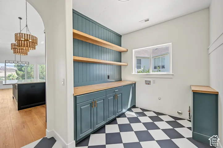 Checkerboard flooring, built-in cabinetry with wood countertops, open wood shelving, and a window for natural light
