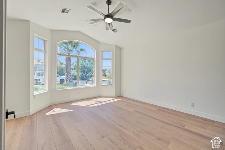 Spacious room featuring light wood-finish flooring and a contemporary ceiling fan with integrated lighting