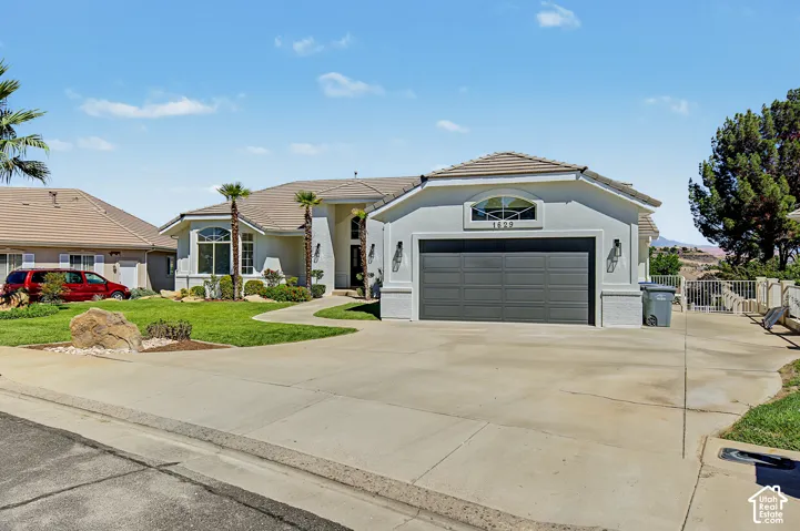 Stucco exterior with a tiled roof, arched window above the garage, and a concrete driveway