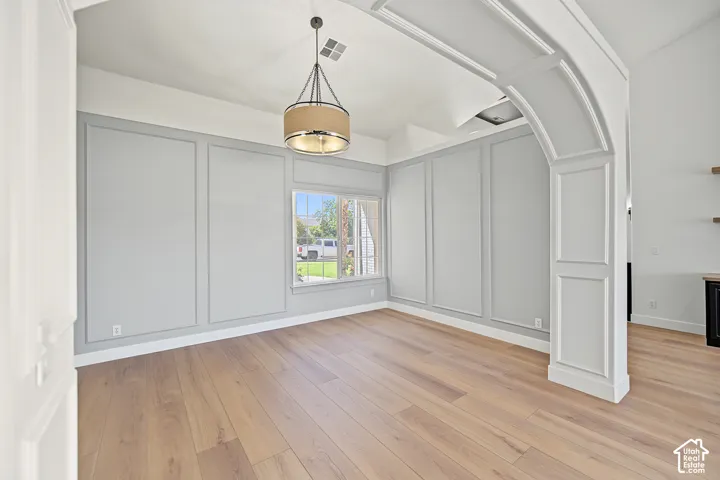Wood-finish flooring with decorative wall paneling and a drum pendant light fixture