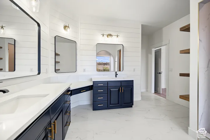 Dual vanity with white countertops, dark cabinetry, and gold-finish hardware