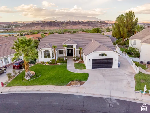 White exterior with a dark tile roof, a two-car garage, and a concrete driveway