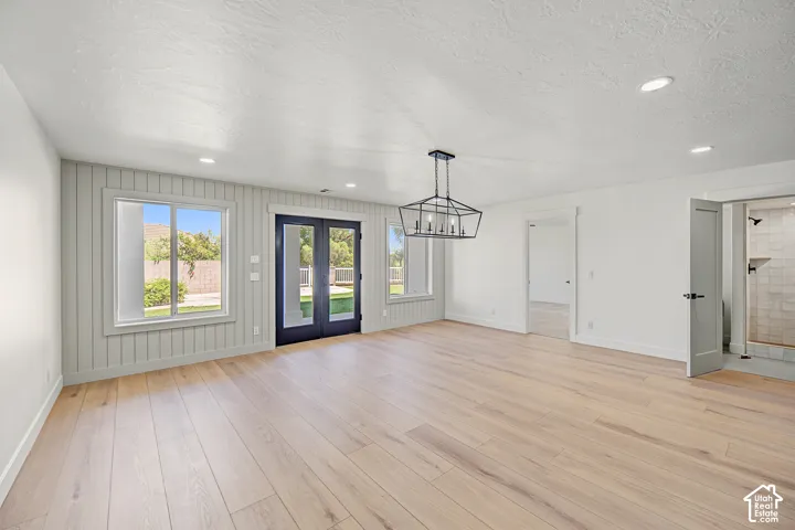 Wood-finish flooring, recessed lighting, and a modern geometric chandelier illuminate this expansive room