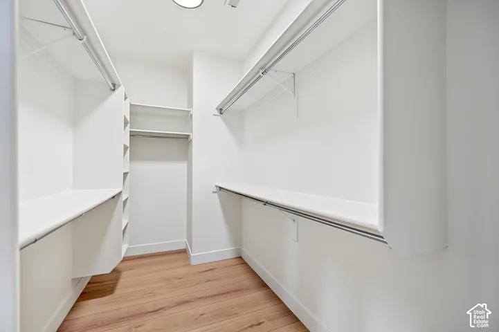 White built-in shelving, integrated hanging rods, recessed lighting, and wood-finish flooring
