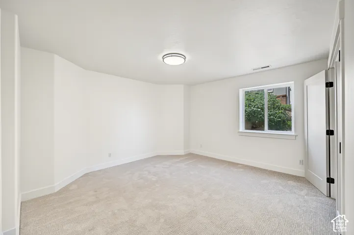 Neutral-toned carpeting, white walls, and a contemporary ceiling light fixture