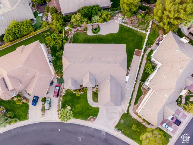 Expansive backyard with a manicured lawn, established landscaping, and paved patio area